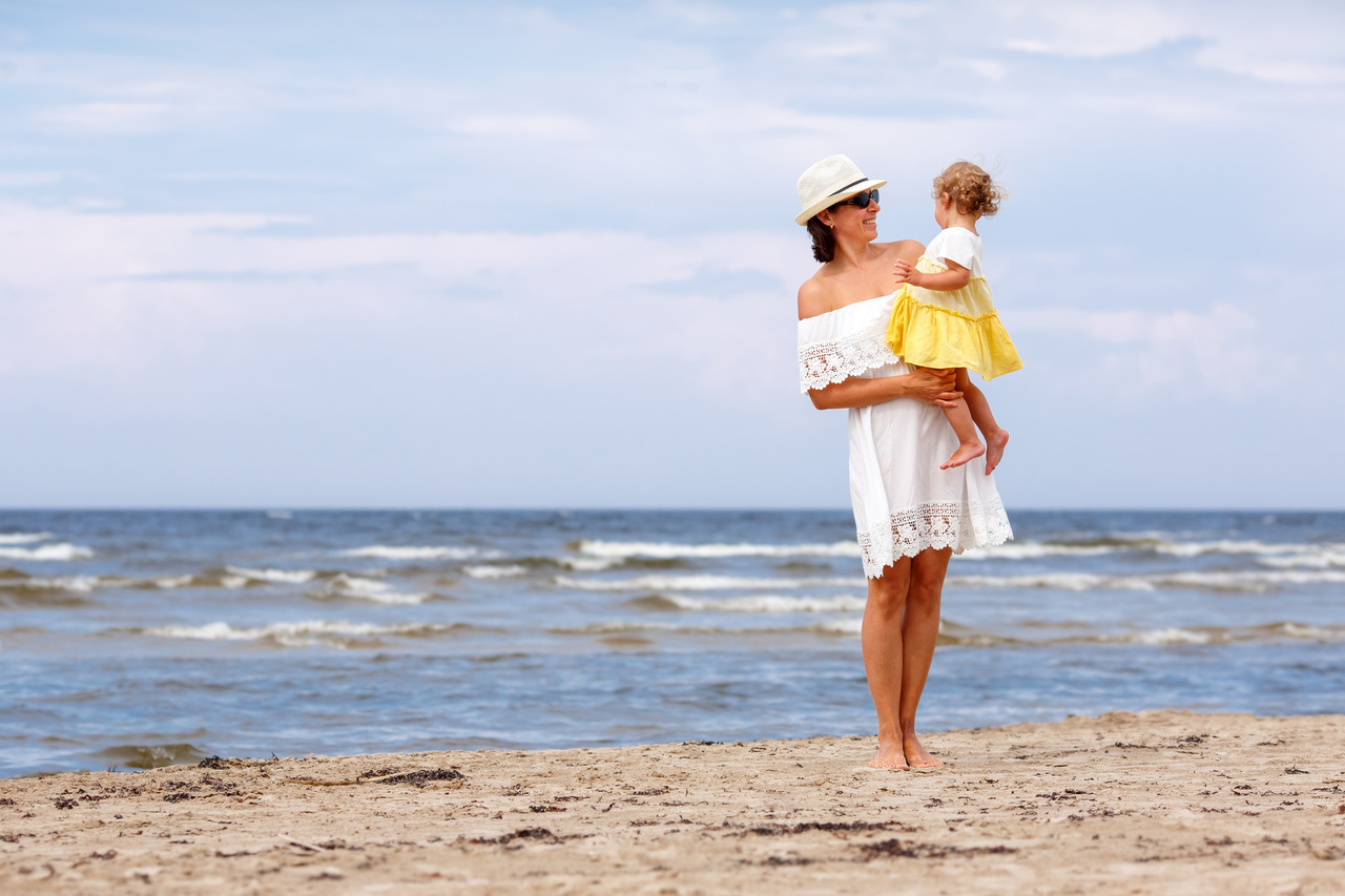 Świnoujście noclegi – mama trzymająca córkę na rękach na plaży